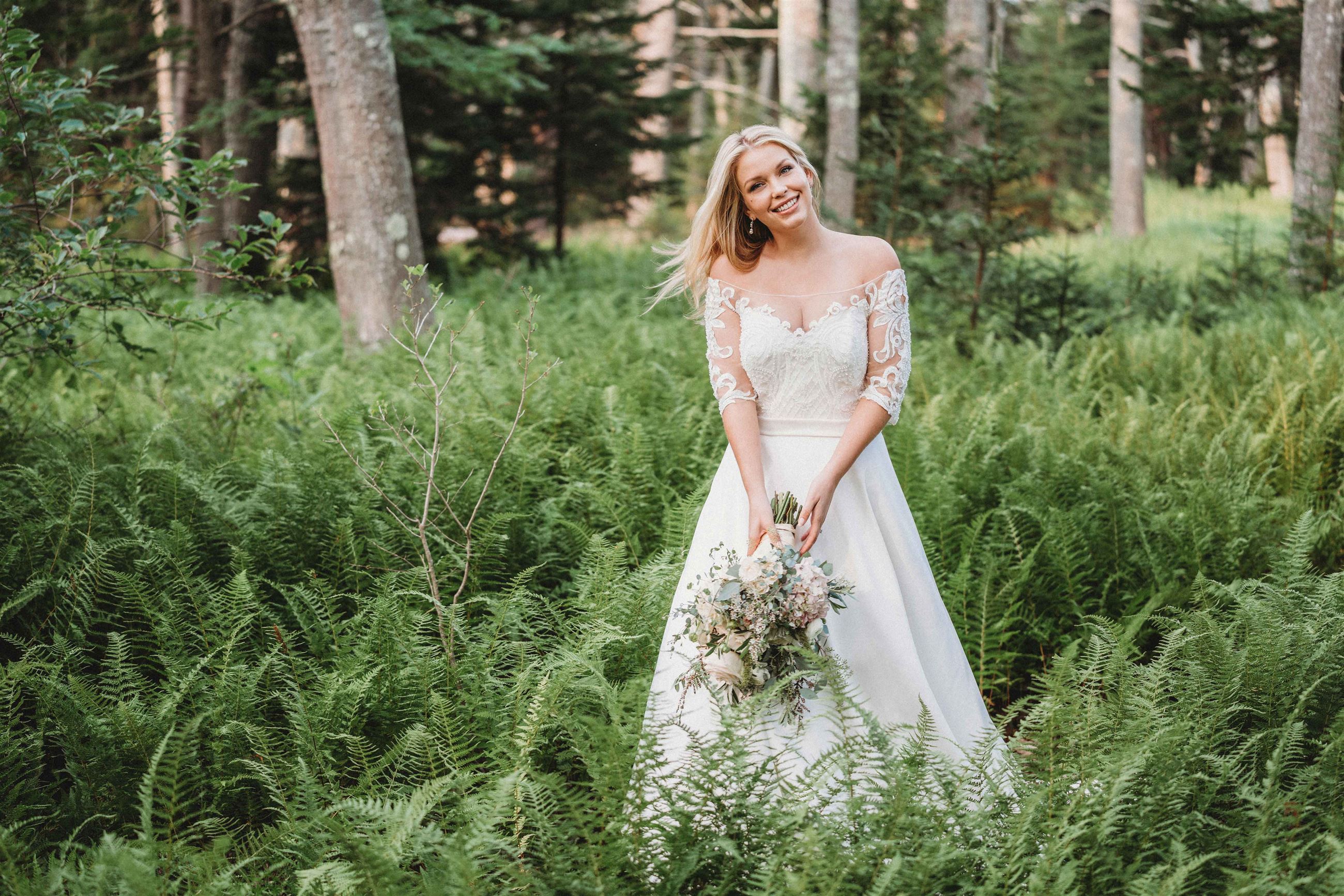 Smiling blonde bride in white wedding dress in forest